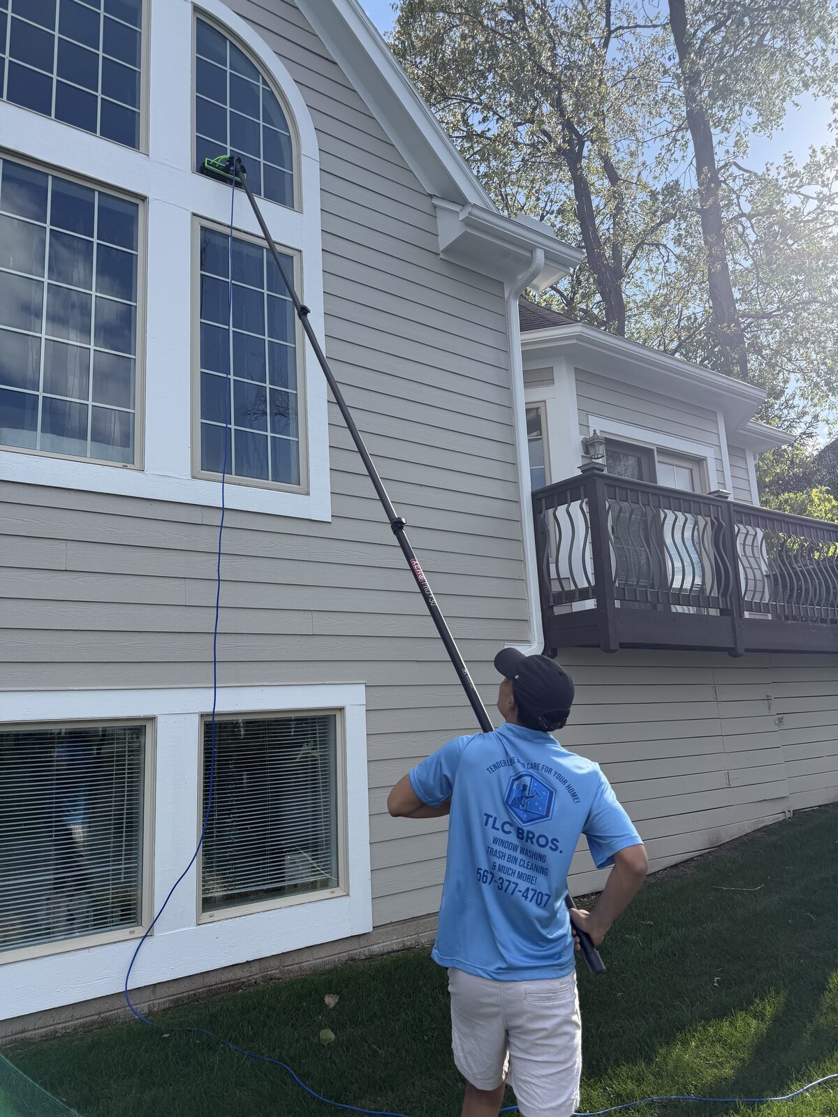 TLC Bros. cleaning second-story windows with a water-fed pole
